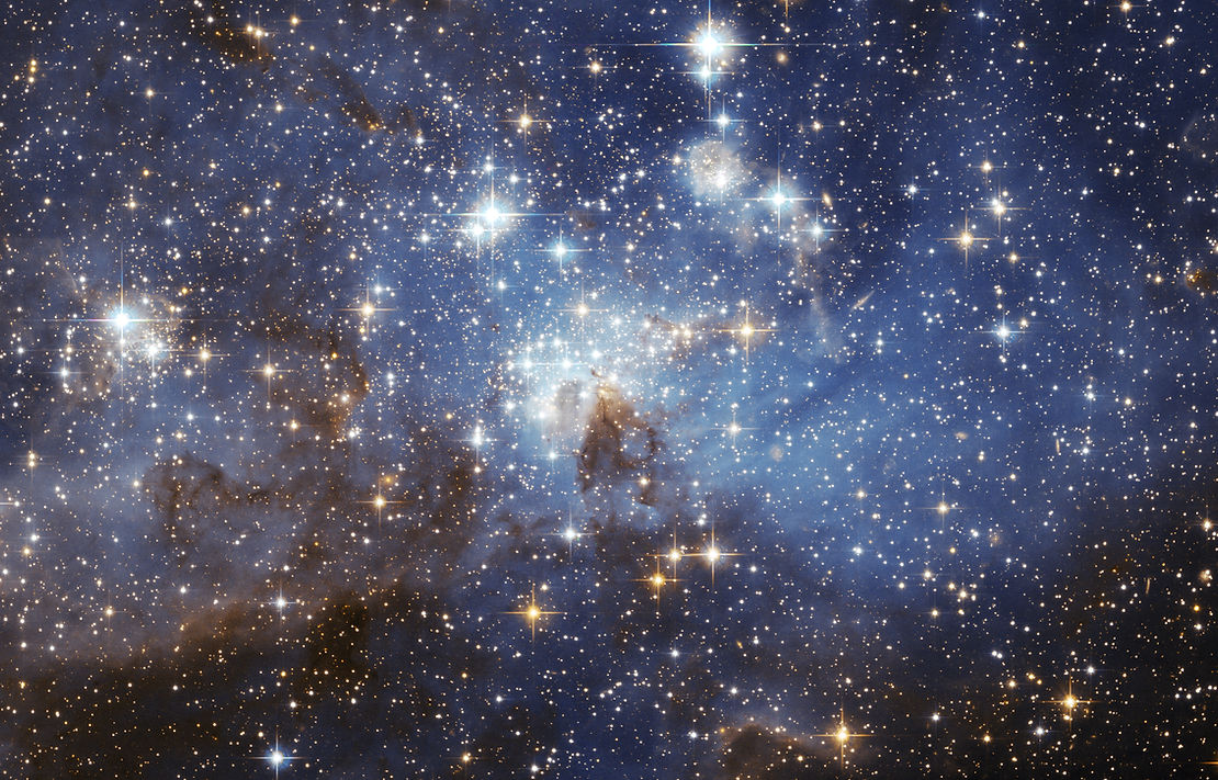 Thousands of bright stars dominate a light, dusty region.
